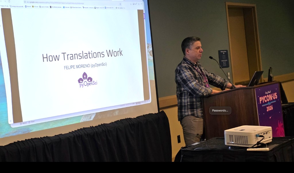 Felipe Moreno presents How Translations Work for pyOpenSci at the PyCon US Maintainer Summit in Long Beach, with a slide showing the pyOpenSci logo projected on screen.